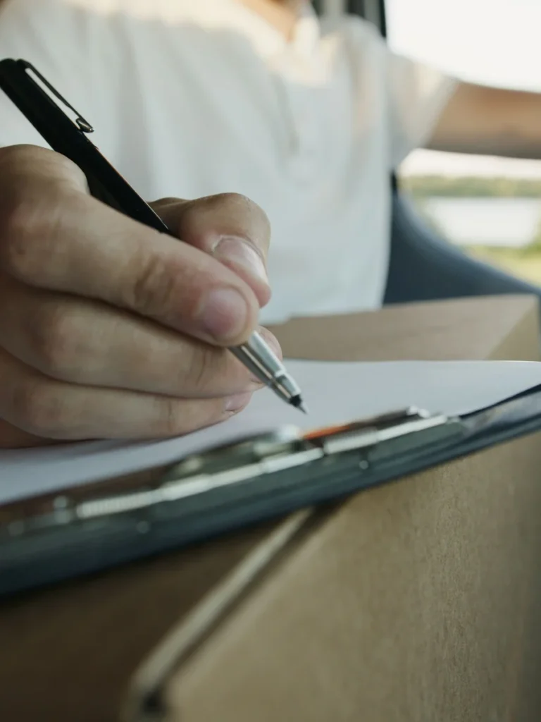 Mano firmando un documento en un portapapeles